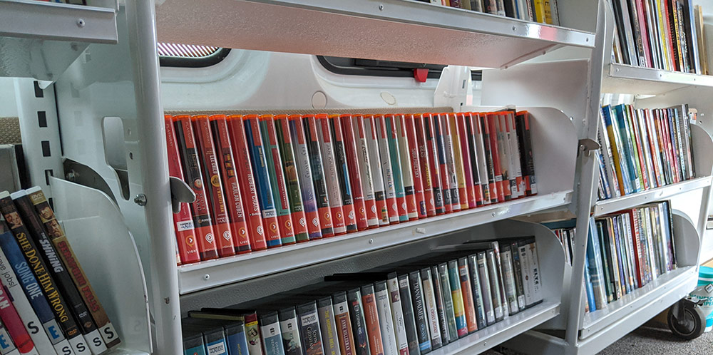 books on CD lined up on a shelf inside of a bookmobile.