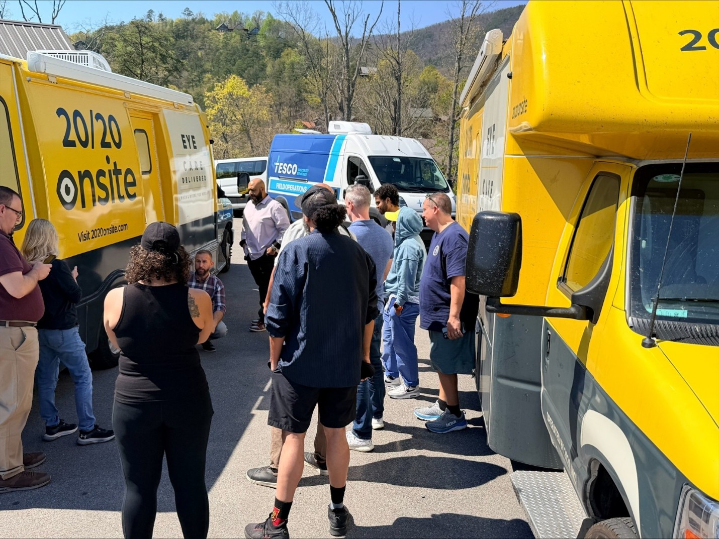 Mobile clinic staff and partners gathered between two 20/20 Onsite vision clinics and a TESCO Field Operations van